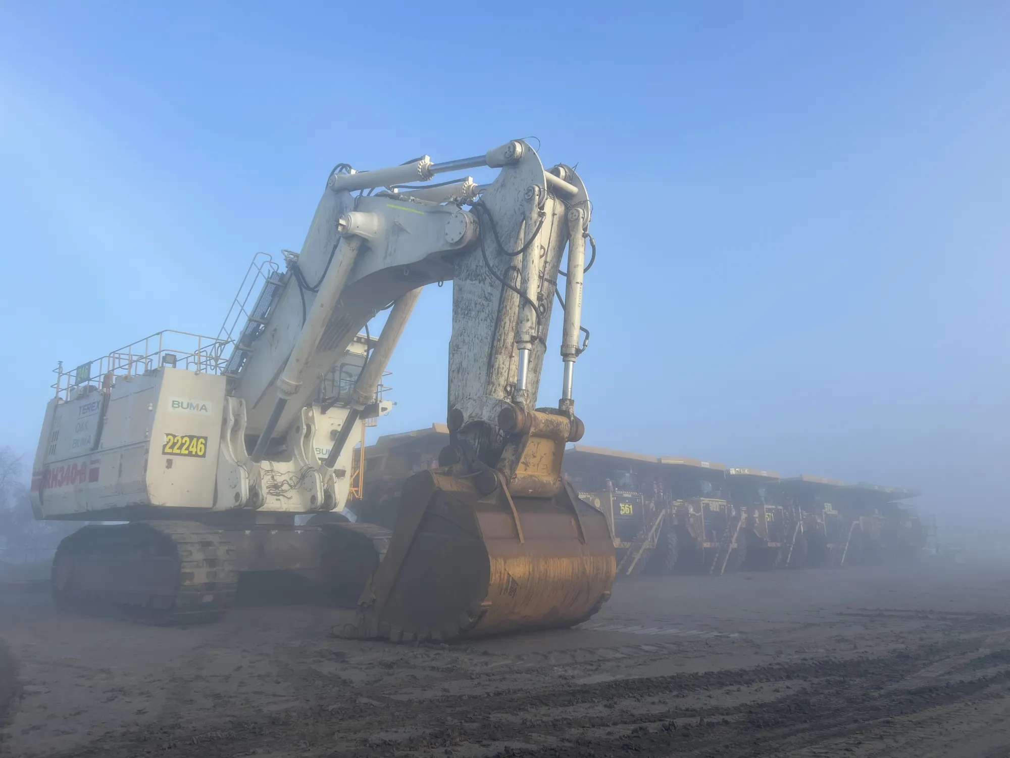 RH340 excavator and haul trucks in morning fog on a coal mine site